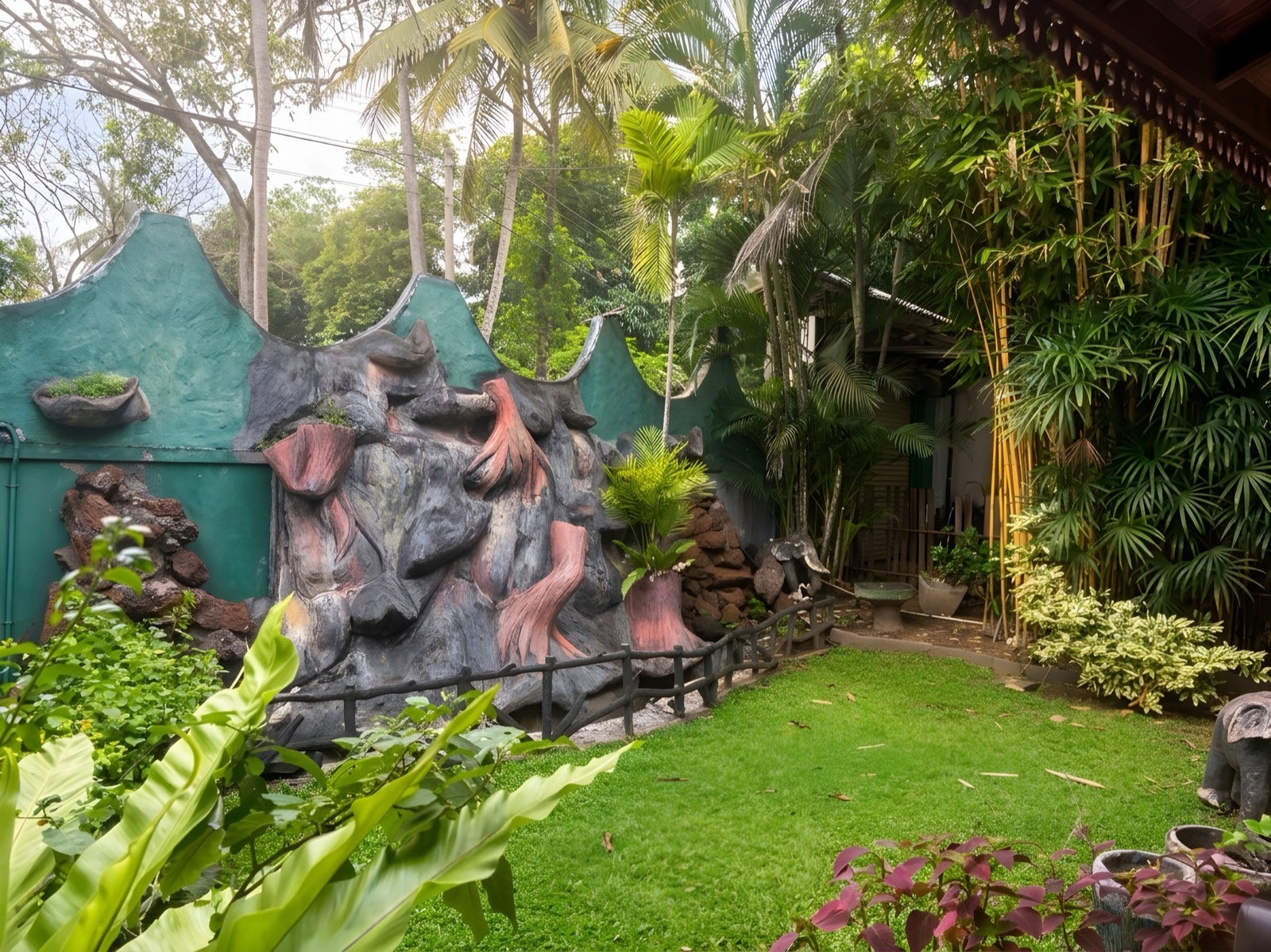 Tropical garden with lawn, palms and a rock water feature
