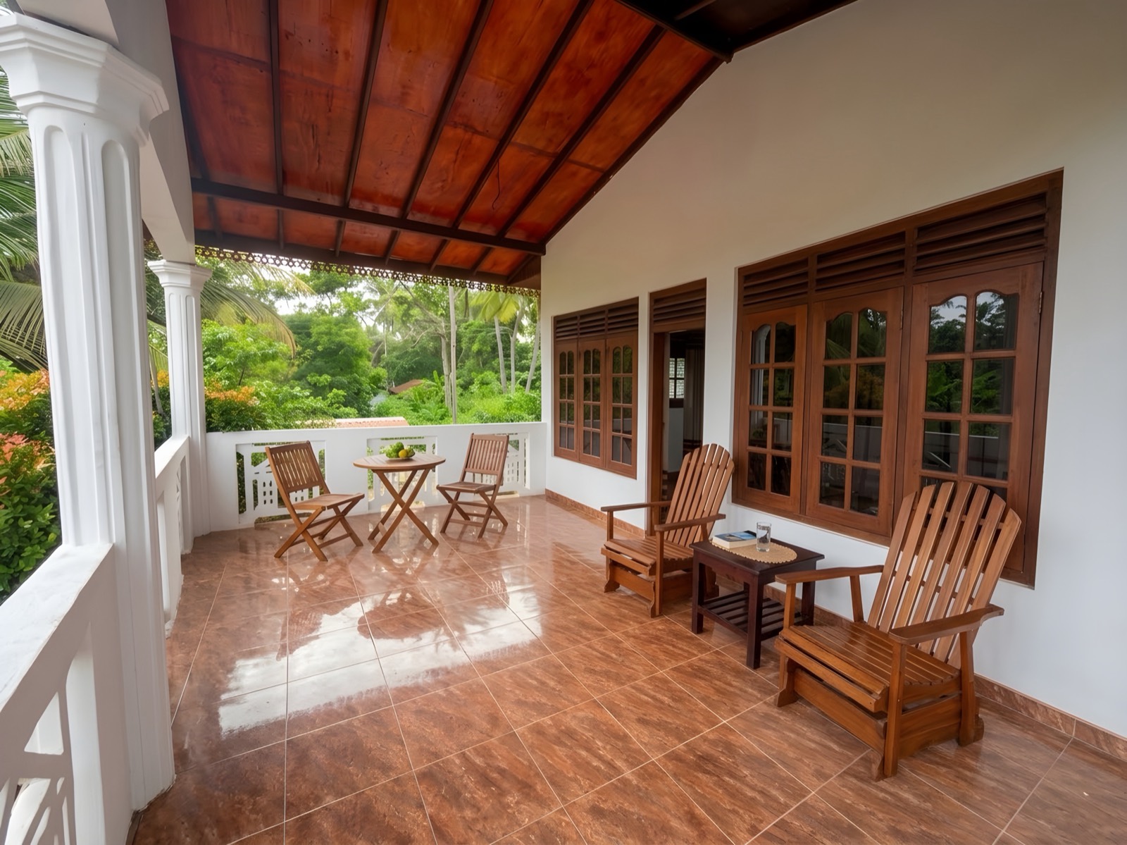 Shaded veranda with wooden chairs overlooking the garden at Hirikatiya Ocean House